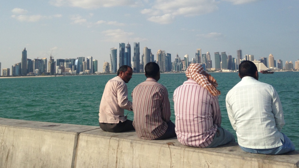 Men talk with the Doha skyline in the background