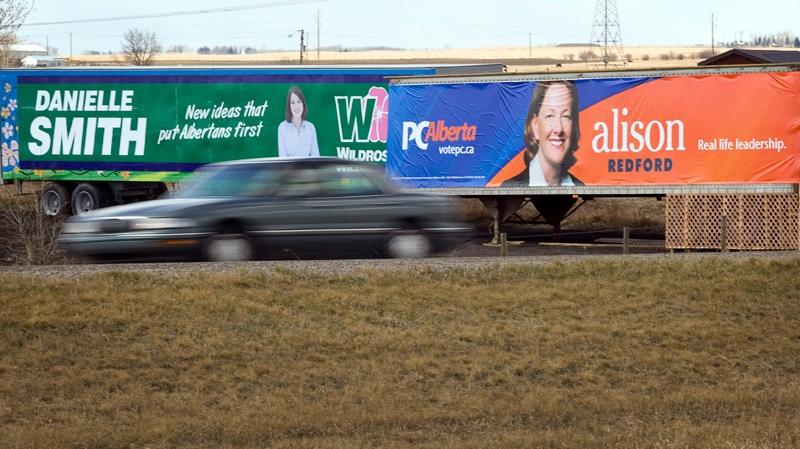 Billboards picturing Alberta PC Leader Alison Redford, right, and Wildrose Leader Danielle Smith look out over traffic on Queen Elizabeth Highway II near Highriver, Alta., Thursday, April 19, 2012. (Jeff McIntosh / THE CANADIAN PRESS)