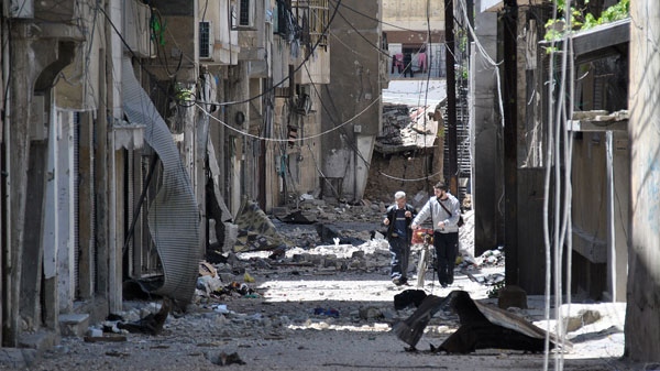 Syrians walk in destroyed alley damaged from Syrian army forces shelling, at Bab Sbaa neighborhood in Homs province, central Syria, Saturday, April 21, 2012. (AP)