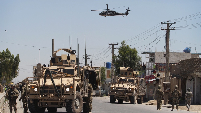 U.S. soldiers and their armored vehicles secure a street as a medevac helicopter flies in sky during an attack at the governor's compound in Kandahar south of Kabul, Afghanistan, Saturday, April 28, 2012.  (AP Photo/Alludddin Khan)