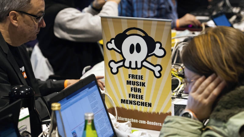 Members of the Pirates party sit next to a poster reading "Free Music for Free People" during their party convention in Neumuenster, northern Germany, Saturday, April 28, 2012. 