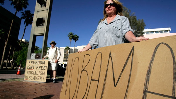  Protesters Jill Henderson and Keith Van Heyningen stand on a street corner waiting for the first lady Michelle Obama to arrive at the Tucson Convention Center in Tucson, Arizona on Monday, April 30, 2012. (AP / Arizona Daily Star, A.E. Araiza) 