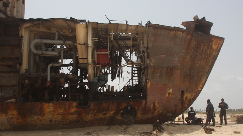 In this photograph taken March 16, 2012, workers gather in the shade of a derelict ship beached against the coastline outside of Lagos, Nigeria. (AP Photo/Jon Gambrell)
