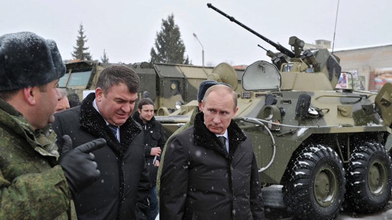 In this Feb. 22, 2012 file photo, Vladimir Putin, right, and Defence Minister Anatoly Serdyukov examine military equipment and weapons during a visit to the Taman Motorized Infantry Brigade in Moscow . At left is lieutenant colonel Andrei Alexeyev. (AP Photo/RIA-Novosti, Alexei Nikolsky, Government Press Service)