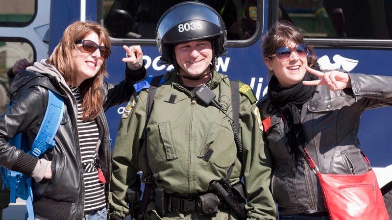 Two female demonstrators pose with a police officer in riot gear after a tentative agreement with students became public Saturday, May 5, 2012 as the Quebec Liberal Party is meeting in Victoriaville Que.. THE CANADIAN PRESS/Jacques Boissinot