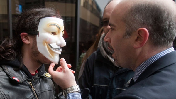 A hotel employee tries to remove the mask of a protester who was part of a crowd blocking the Delta hotel during a demonstration against higher tuition fees in Montreal, Thursday, February 16, 2012. (Ryan Remiorz / THE CANADIAN PRESS)