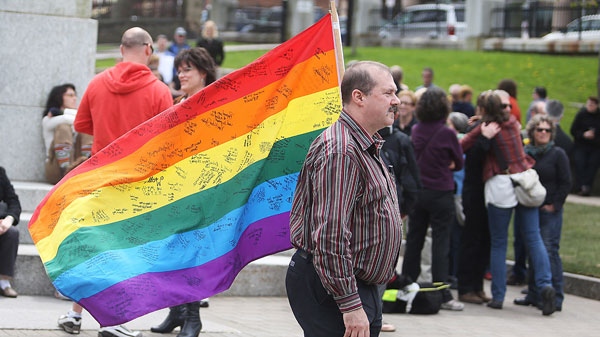 Daniel MacKay carries a rainbow flag with messages for Raymond Taavel at Grand Parade prior to a public memorial service in Halifax. N.S. on Sunday, May 6, 2012. (Ryan Taplin / THE CANADIAN PRESS)