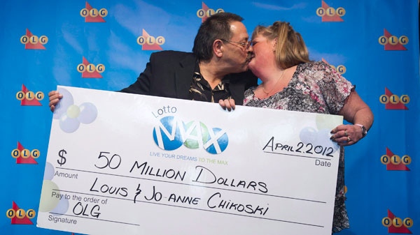 Former Lotto Max winner Louis Chikoski kisses his wife Jo-Anne Chikoski as they show off their $50-million Lotto Max cheque in Toronto on Monday, April 2, 2012. (Nathan Denette / THE CANADIAN PRESS)