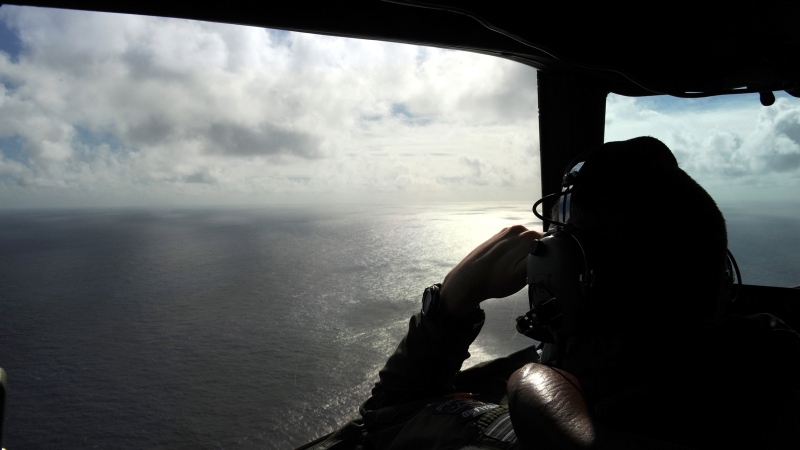In this April 13, 2014 file photo taken from the Royal New Zealand air force (RNZAF) P-3K2-Orion aircraft, pilot and aircraft captain, Flight Lt. Timothy McAlevey looks out of a window while searching for debris from missing Malaysia Airlines Flight 370, over the Indian Ocean off the coast of western Australia. (AP / Greg Wood, Pool, File)