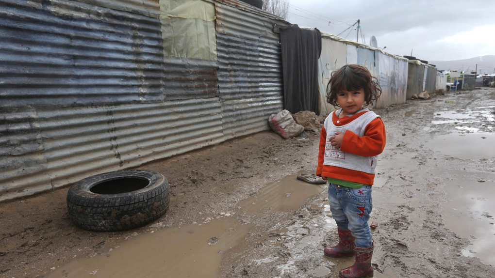 A Syrian girl stands in mud 