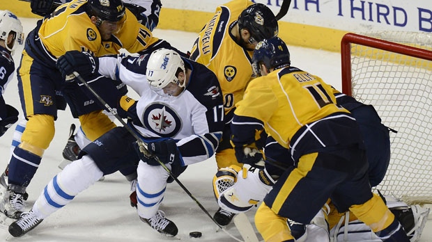 Winnipeg Jets left wing Adam Lowry (17) tries to get control of the puck as he is defended by Nashville Predators defenseman Mattias Ekholm, top left, of Sweden, Mike Santorelli, top center, and Ryan Ellis, right, in the second period of an NHL hockey game Saturday, March 7, 2015, in Nashville, Tenn. (AP Photo/Mark Zaleski)