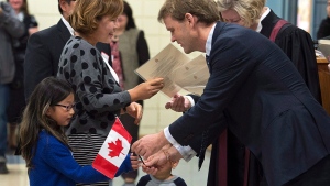 Chris Alexander, citizenship and immigration minister, hands out a Canadian flag at a citizenship ceremony in Dartmouth, N.S., on Tuesday, Oct. 14, 2014. (THE CANADIAN PRESS/Andrew Vaughan)