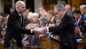 Finance Minister Joe Oliver hands a copy of the federal budget to a clerk in the House of Commons, on Tuesday, April 21, 2015. (THE CANADIAN PRESS/Adrian Wyld)