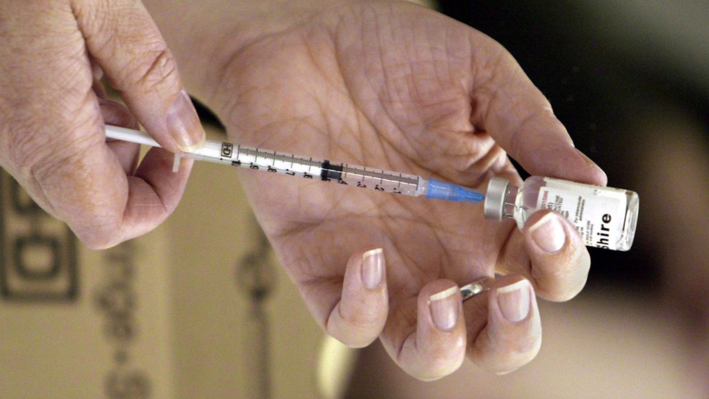 A nurse loads a measles syringe
