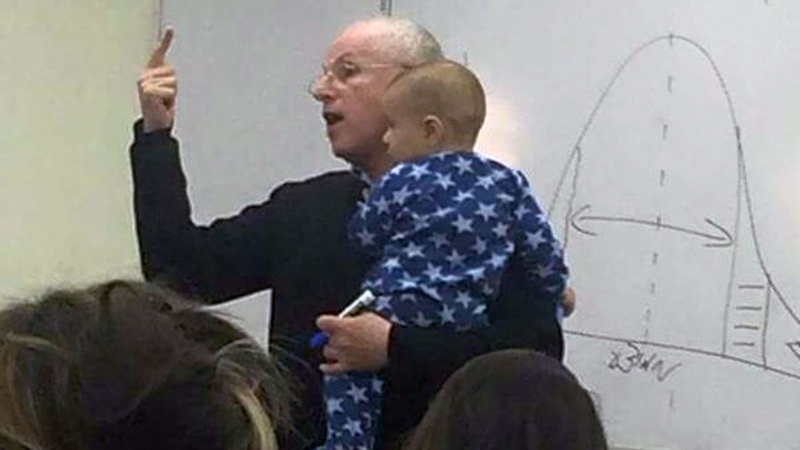 In this Facebook photo, Prof. Sydney Engelberg holds the baby of a student while he lectures on organizational behaviour. (Sarit Fishbaine / Facebook)