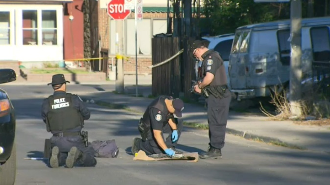 Police examine the scene of a fatal shooting in Toronto on Thursday, May 21, 2015. 
