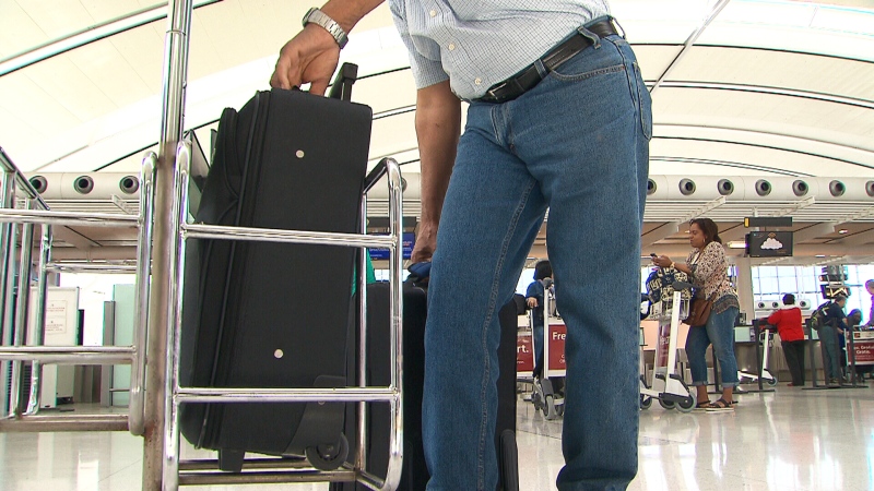 A passenger fits his luggage into a carry-on bag sizing device that may be used more often as Air Canada is set to begin cracking down on carry-on baggage.