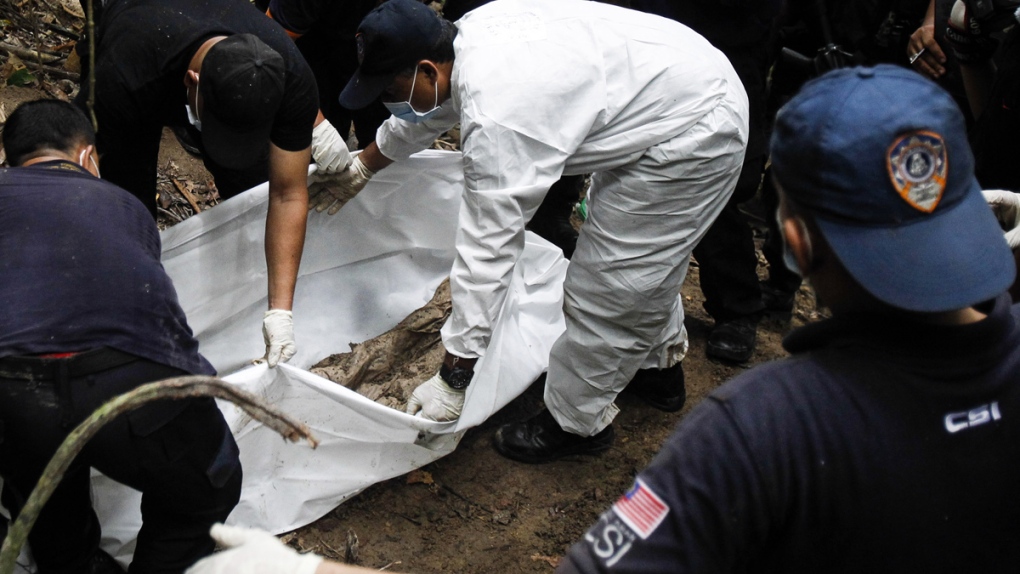 Malaysian police forensic team exhumes grave site