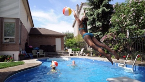 Julia Lowther, 12, reaches for a beach ball as parents Deb and Stuart look on in the family's backyard pool in Burlington, Ont., Sunday, June 1, 2014.  (Galit Rodan / THE CANADIAN PRESS)
