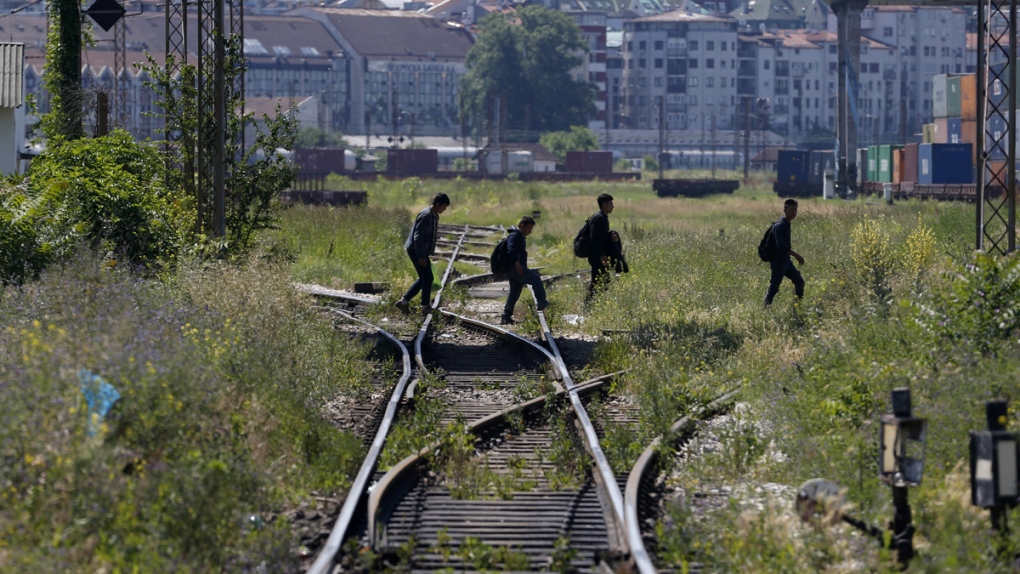 Migrants cross railroad tracks in Belgrade, Serbia