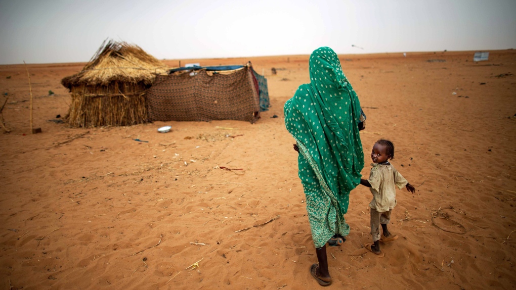 Sudanese woman holds daughter's hand