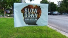 A lawn sign urges motorists to slow down on residential streets. 