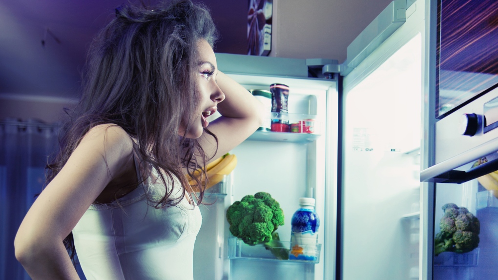 Woman looks inside fridge