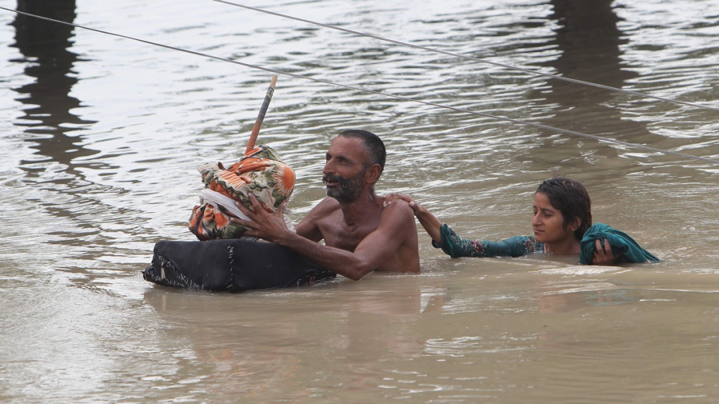 Wading through floodwaters in Rajanpur, Pakistan