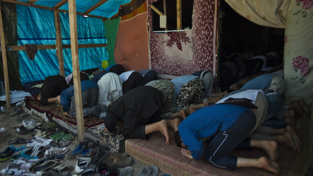 Afghan migrants pray at a makeshift mosque