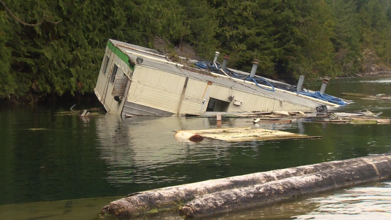 A half-sunk logging barge is seen in the inlet off the village of Zeballos, B.C., one of the communities to receive the new flood-mitigation funding. (CTV News)