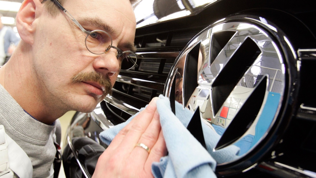 A worker polishes a Volkswagen emblem