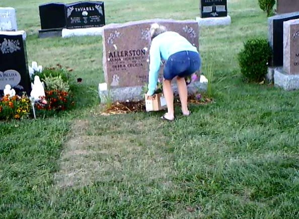 A woman is seen pulling flowers from a grave site at St. Peter's Cemetery in London, Ont. in this image released by London police.