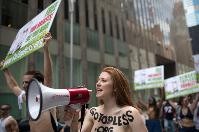 Rachel Jessee speaks into a megaphone while riding atop a car during the GoTopless Day Parade, Sunday, Aug. 23, 2015, in New York.  (AP / Kevin Hagen)