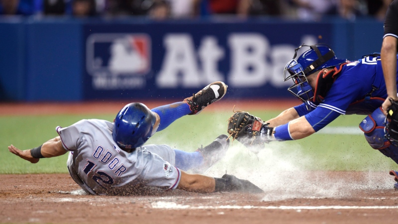 Toronto Blue Jays' catcher Russell Martin, right, misses the tag on Texas Rangers' Rougned Odor as he scores on a sacrifice fly by Hanser Alberto in Toronto on Oct. 9, 2015. (Frank Gunn / The Canadian Press)