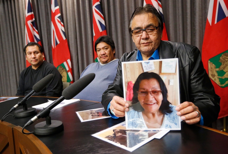 Aboriginal and Northern Affairs Minister Eric Robinson (right) holds a photo of Rebecca Barkman as Norman Barkman (left) and Luke Monias (centre) look on at the Manitoba Legislature Nov. 13, 2015. The two Garden Hill First Nation men were born to Rebecca Barkman and Rosamund Monias and switched at birth. (THE CANADIAN PRESS/John Woods)