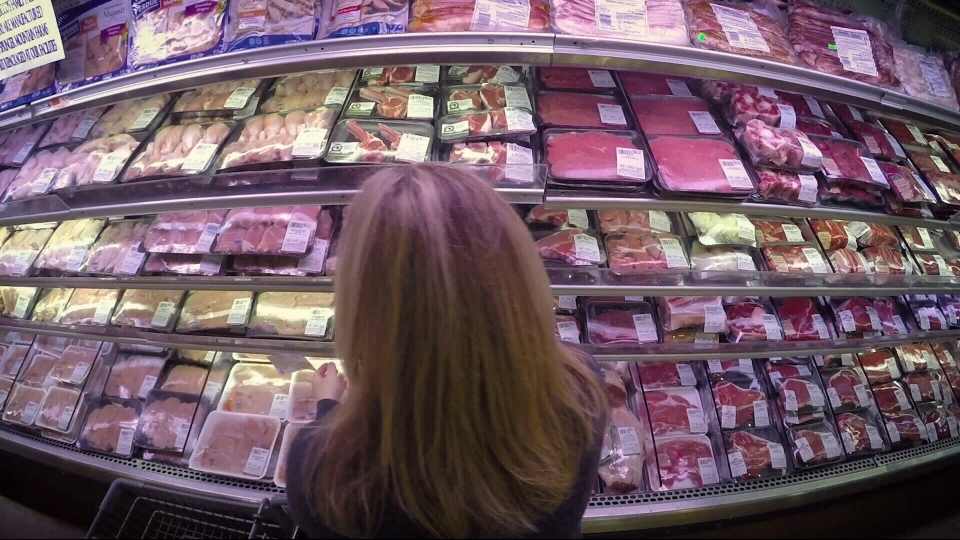 Woman standing in front of meat counter in superma