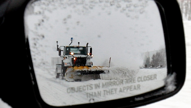 A snow plow is reflected in a sideview car mirror on Highway 401 on Sunday, Dec.16, 2007. (The Canadian Press/J.P. Moczulski