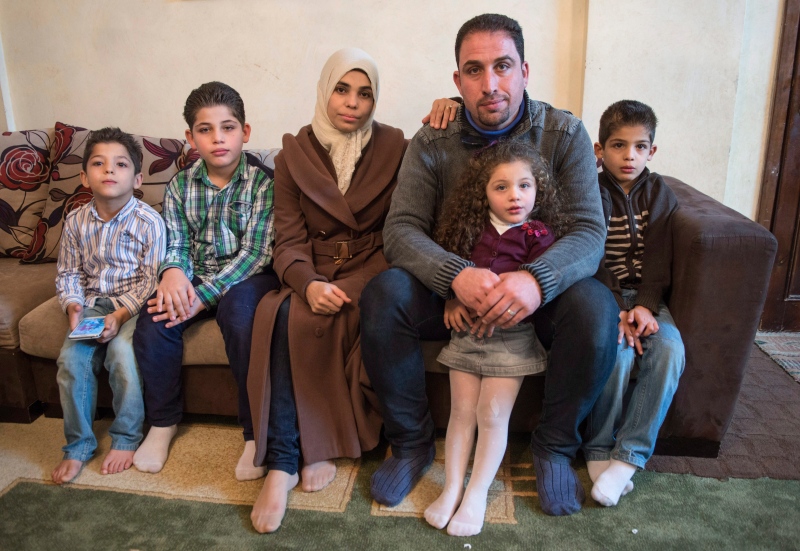 Syrian refugee Awad Alhajali from Kherbet Ghazalah, Syria and his wife Asmaa sit with their children, Obaida, 5, Adnan, 9, Abedr, 2, and Obada, 7, left to right, in their apartment on November 30, 2015 in Irbid, Jordan. The family is waiting for approval to immigrate to Canada. (Paul Chiasson / The Canadian Press)