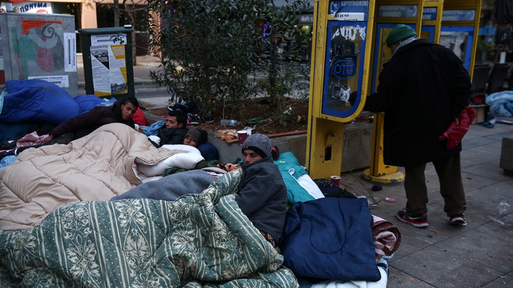Migrants try to keep warm in streets of Athens