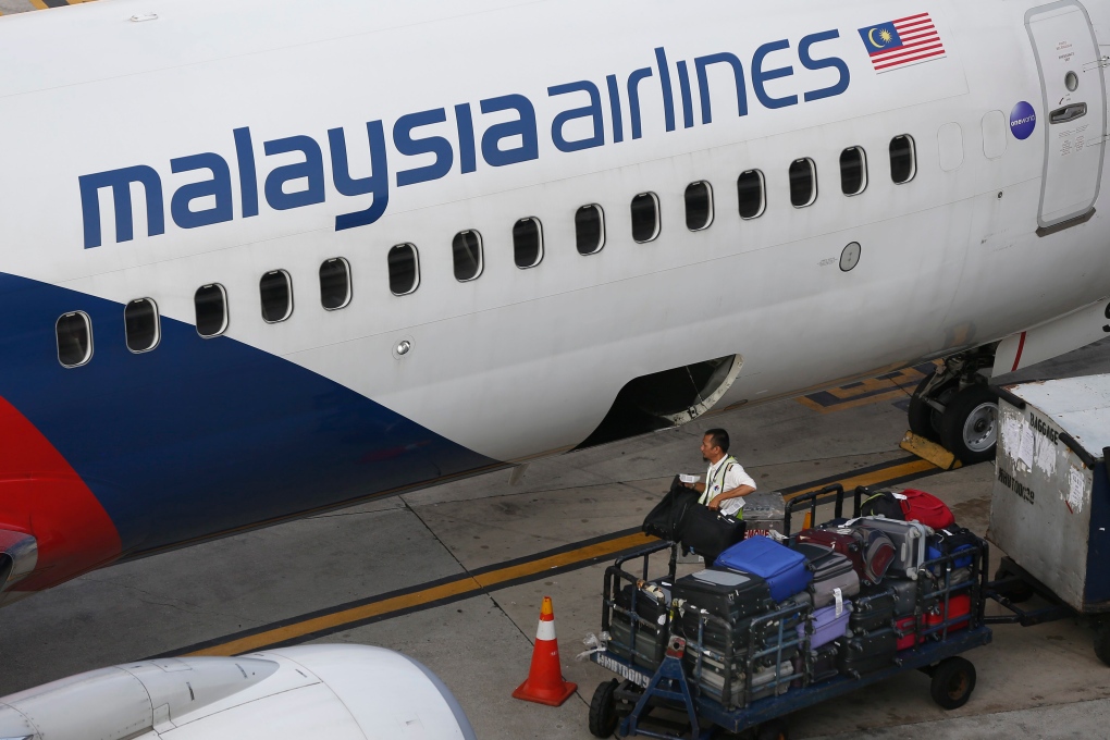 Staff member loads bags on Malaysia Airlines plane