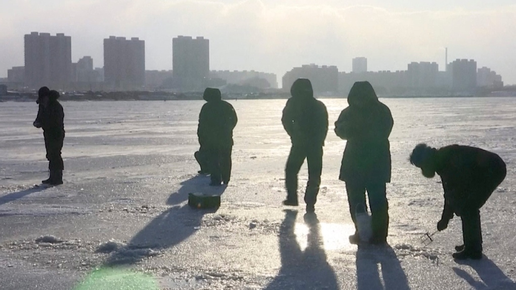 North Koreans stand on the frozen Taedong River