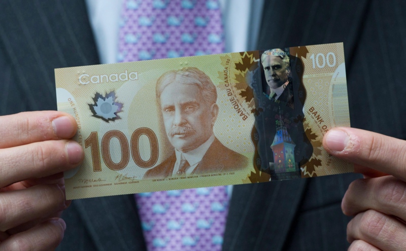 Then-Bank of Canada Governor Mark Carney holds a new $100 bill as he unveils polymer bank notes in $50 and $100 denominations at the Bank of Canada in Ottawa on Monday, June 20, 2011. (Sean Kilpatrick/THE CANADIAN PRESS)
