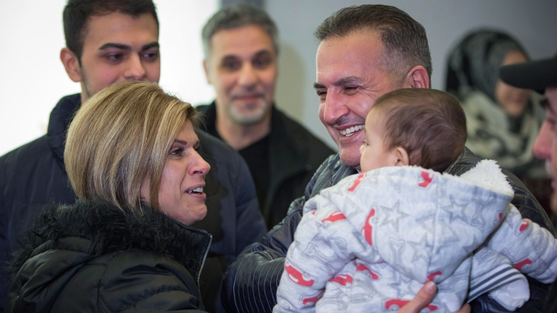 Tima Kurdi, left, who lives in the Vancouver area, embraces her brother Mohammad Kurdi and his 5-month-old son Sherwan Kurdi after her brother and his family, who escaped the war in Syria, arrived at Vancouver International Airport, in Richmond, B.C., on Monday, Dec. 28, 2015. (THE CANADIAN PRESS / Darryl Dyck)