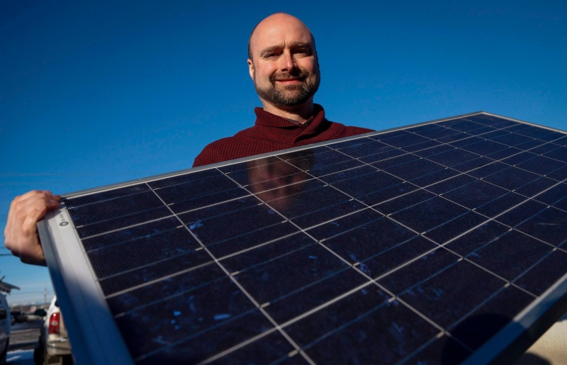 Curtis Buxton, a project manager at Skyfire Energy Inc., who was forced to look for new employment after being downsized out of the oil and gas industry, poses with solar panels, in Calgary on Monday, Jan. 25, 2016. (Jeff McIntosh/THE CANADIAN PRESS)