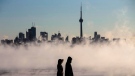 Steam rises as people look out on Lake Ontario in front of the skyline during extreme cold weather in Toronto on Saturday, Feb. 13, 2016. (Mark Blinch / THE CANADIAN PRESS)