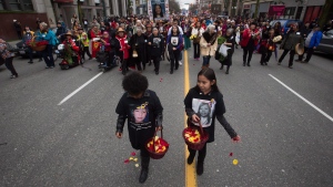 Young girls scatter flower petals on the ground while leading hundreds of people through the Downtown Eastside during the 25th annual Women's Memorial March in Vancouver, B.C., on Saturday, Feb. 14, 2015. (THE CANADIAN PRESS / Darryl Dyck)