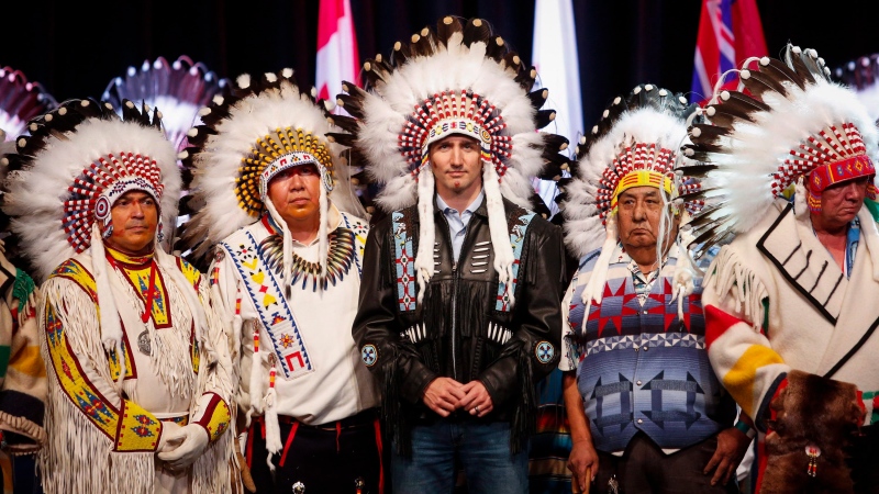 Prime Minister Justin Trudeau poses with elders after receiving a ceremonial headdress while visiting the Tsuu T'ina First Nation, near Calgary, Alta., on Friday, March 4, 2016. (THE CANADIAN PRESS/Jeff McIntosh)