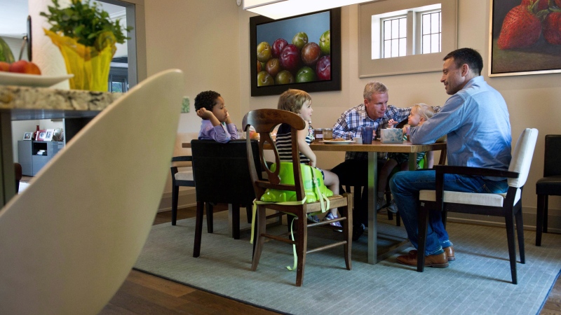 Brian Rosenberg, right, and his husband Ferd van Gameren sit down for lunch with children Levi, 5, and three-year-old twins Sadie, centre, and Ella in Toronto, Monday, June 9, 2014. (Galit Rodan / THE CANADIAN PRESS)