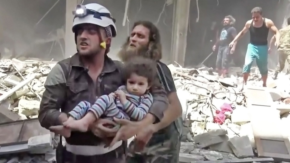 A Civil Defense worker carries a child