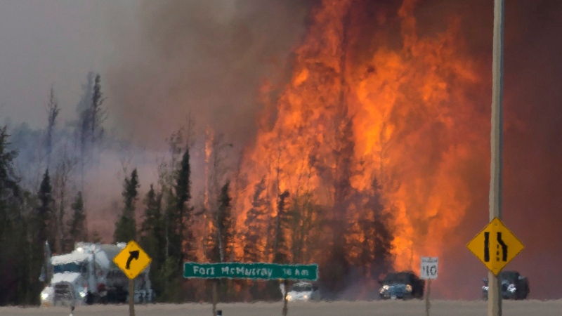 Heat waves are seen as cars and trucks try and get past a wild fire 16km south of Fort McMurray on Highway 63 Friday, May 6, 2016. (Jonathan Hayward / THE CANADIAN PRESS)